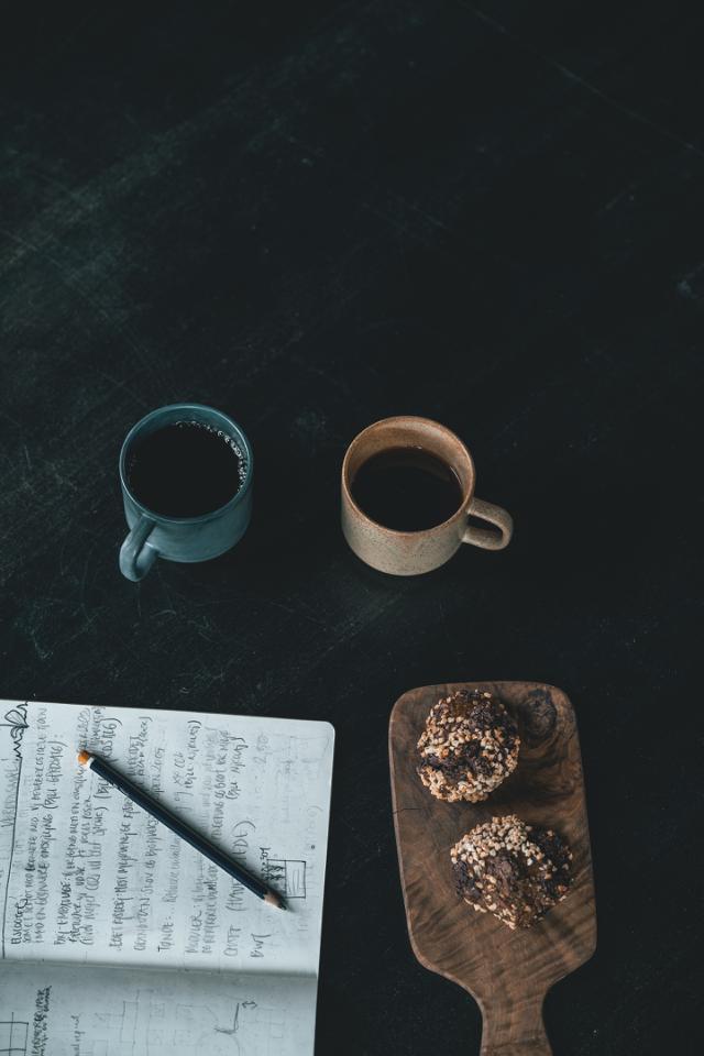 kaffekopper paa skrivebord med notesbog og kage