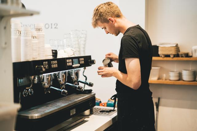 barista brygger kaffe paa en espressomaskine paa cafe