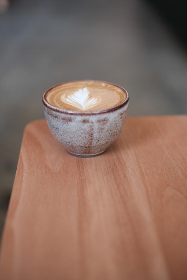 cappuccino med latteart i keramikkop staar paa et bord