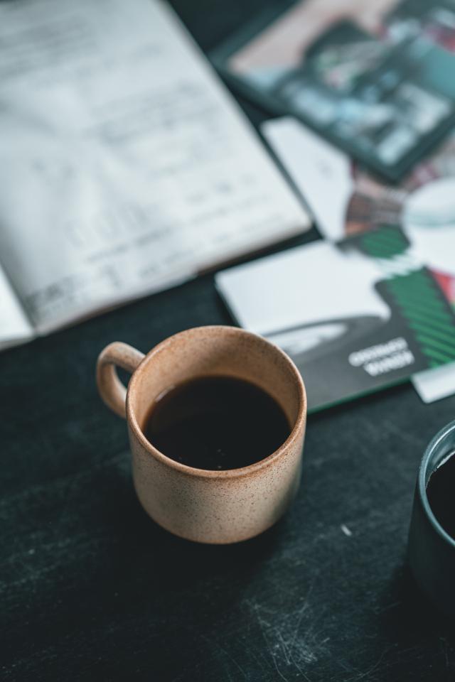 lysristet kaffe i en gul keramik kop paa et bord med papirer