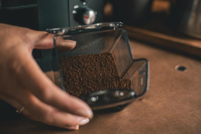 haand holder en beholder med formalet mellemristet kaffe