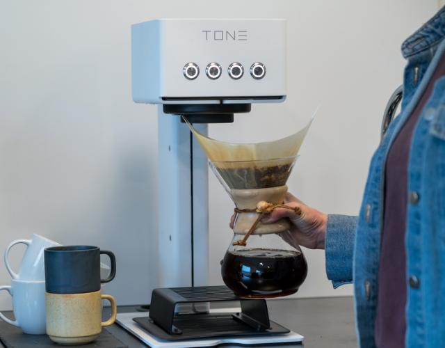 medarbejder går med en kaffe i en chemex brygget på tone